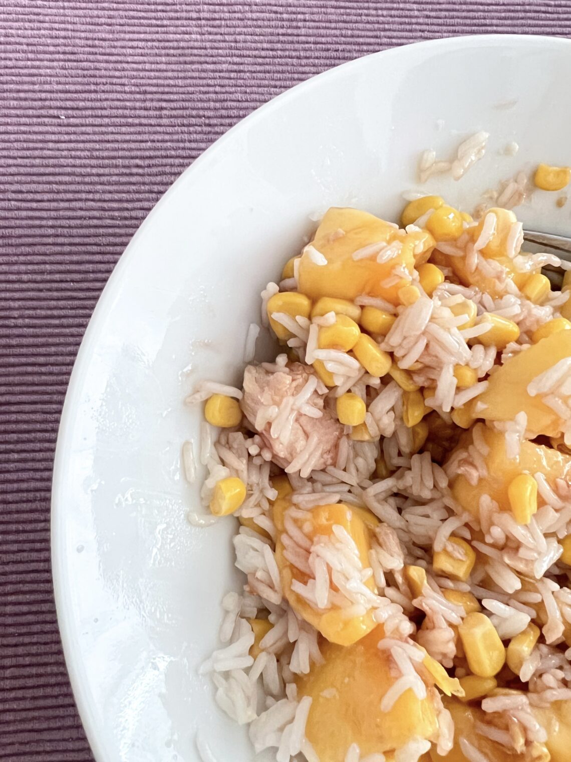 fotografía de la ensalada de arroz y mango en un plato blanco con un mantel morado