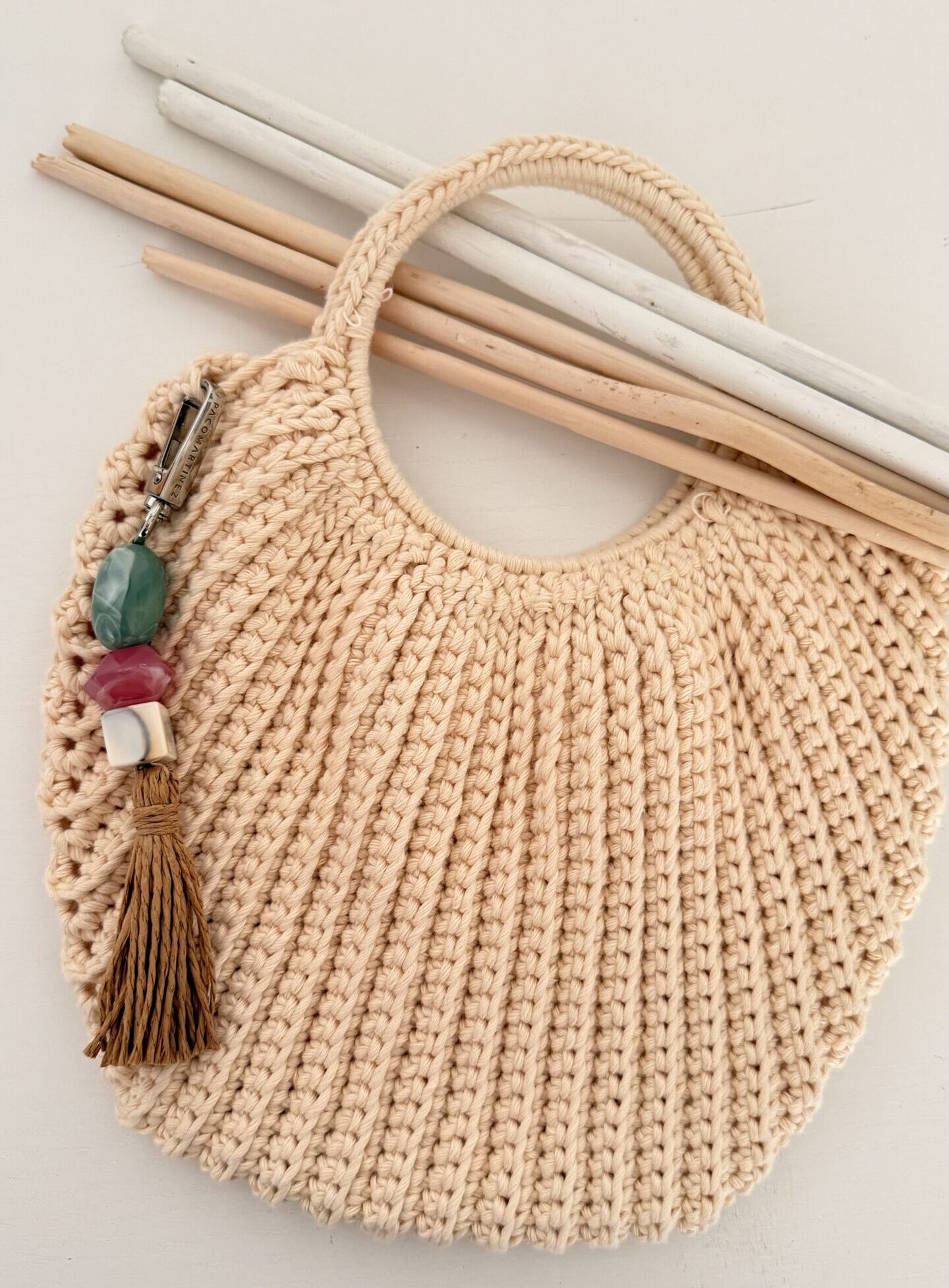 Bolso tejido a mano en tonos naturales con detalle de piedras.