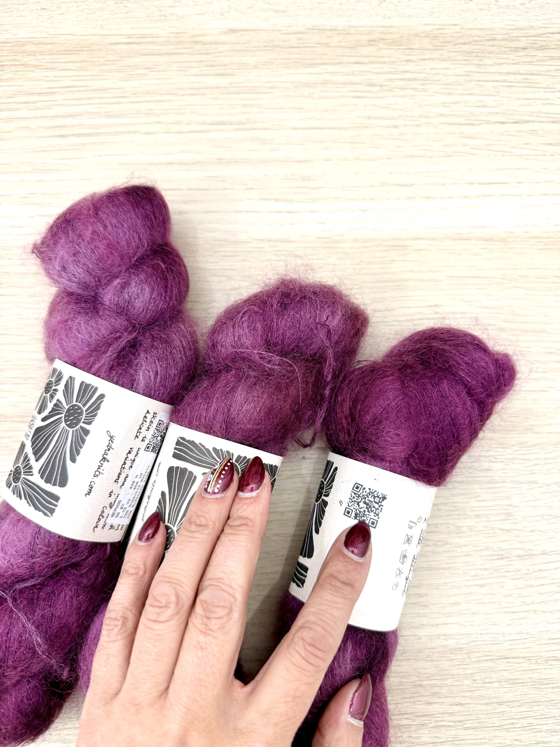 Ovillos de mohair púrpura y etiqueta con información visible.